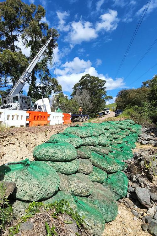 crane placing rocks on side of road